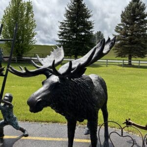 A moose statue is standing in the middle of a road.