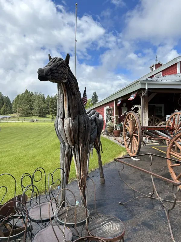 A horse statue in front of a barn.