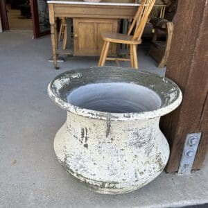 A large white planter sitting on the ground outside.