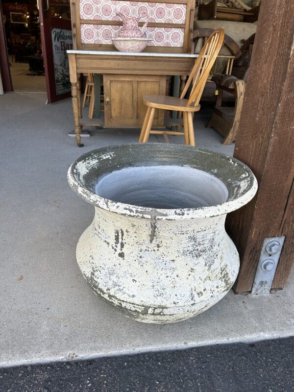 A large white planter sitting on the ground outside.