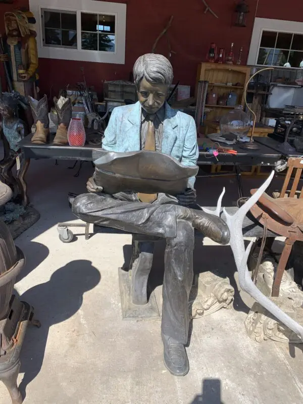 A statue of a man sitting on top of a bench.