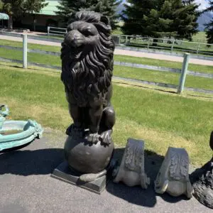 A statue of a lion is sitting on top of a ball.