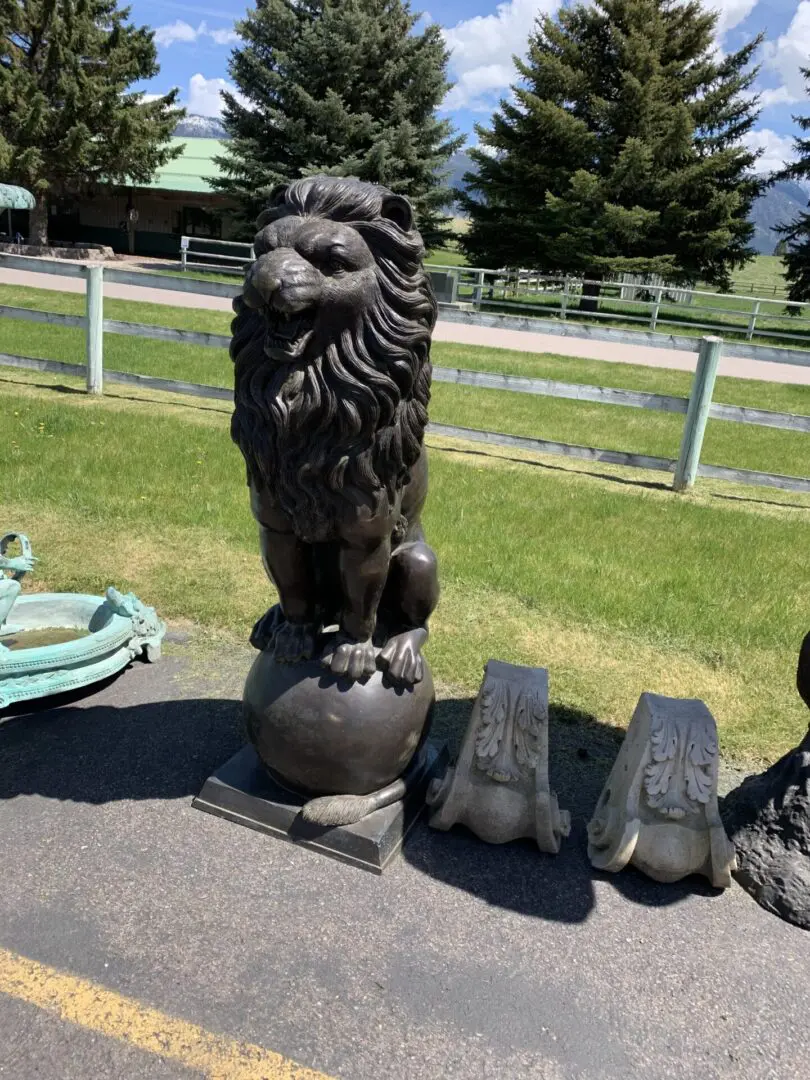 A statue of a lion is sitting on top of a ball.