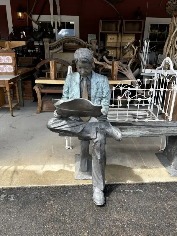 A statue of a man sitting on top of a bench.