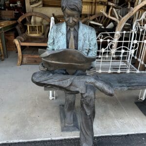 A statue of a man sitting on top of a bench.