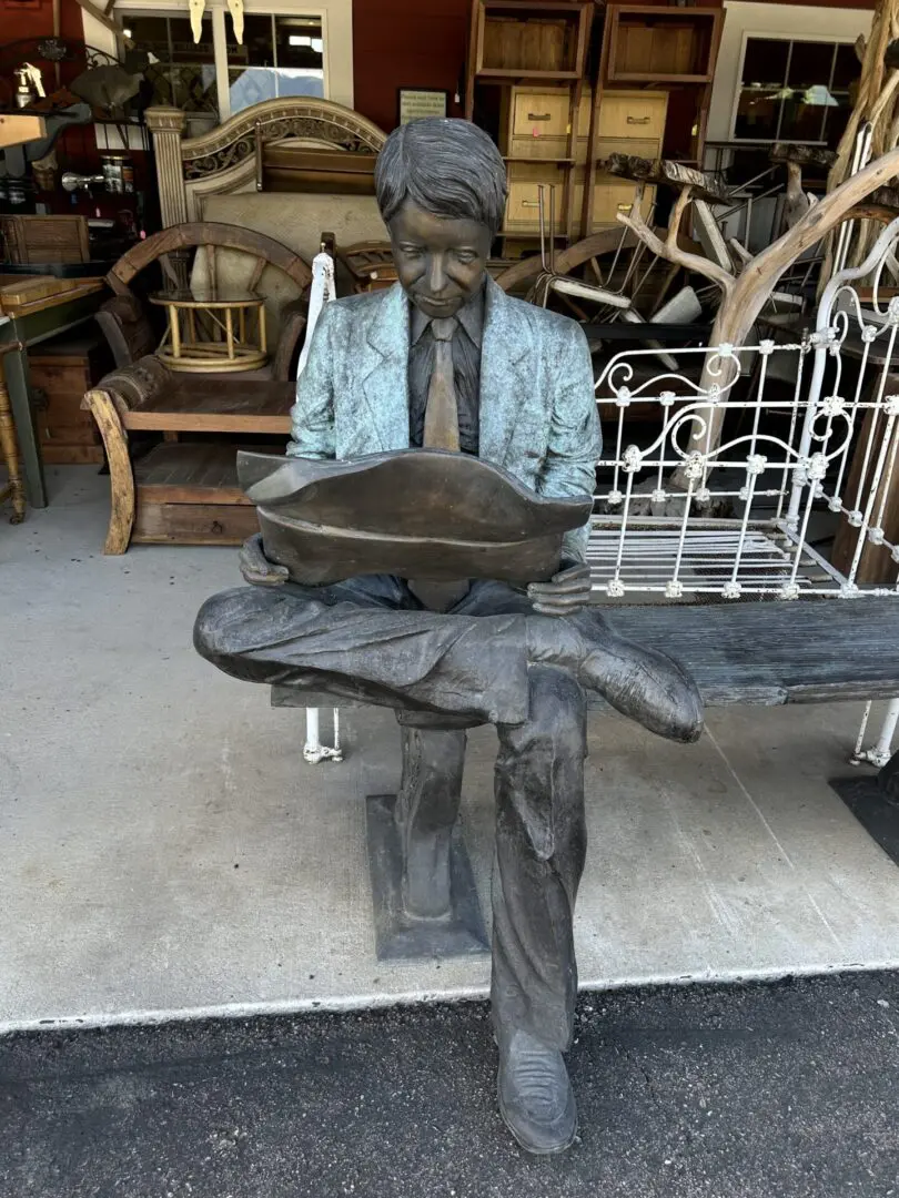 A statue of a man sitting on top of a bench.