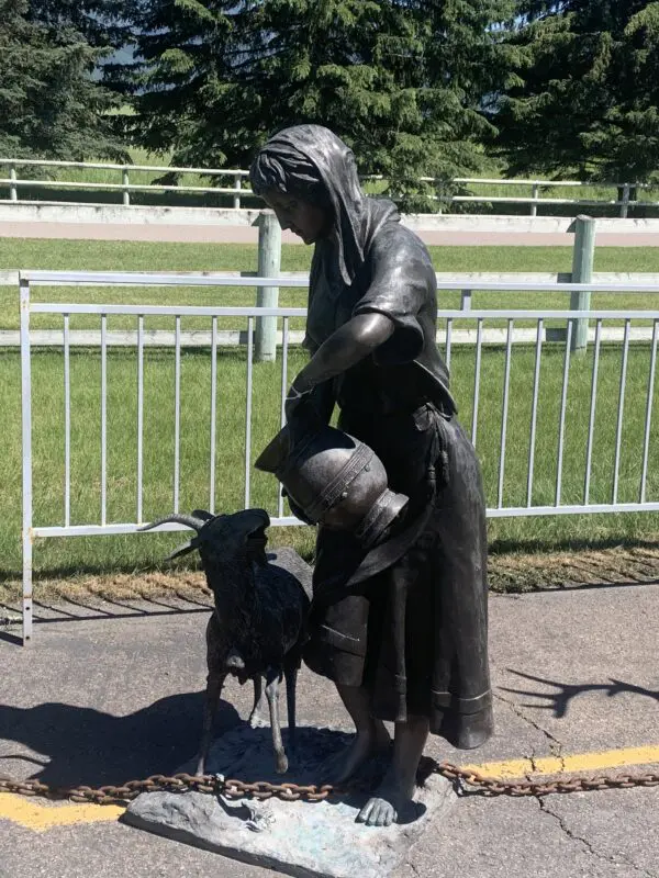 A statue of a woman and her dog on the side walk