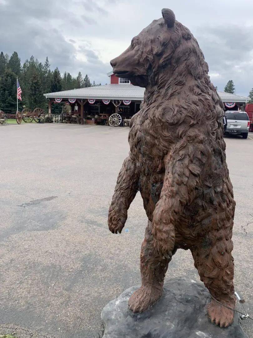 A bear statue in the middle of a parking lot.