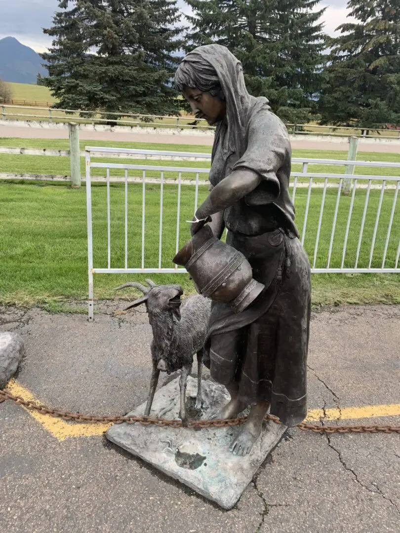 A statue of a woman and goat in the middle of a road.