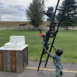 A boy and a monkey climbing on the ladder of a horse.